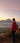 Lottie in a red jacket and yellow backpack standing on a mountain overlooking a scenic landscape with mountains and water.