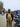 Lottie with a yellow backpack standing on a busy street with motorcycles and people around.