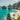 View of Bali beach with clear blue water, rocky cliffs, and palm trees.