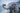 Four friends taking a selfie with a smartphone on a beach with mountains in the background