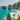 Indonesian beach with clear blue water, rocky cliffs, and palm trees.