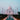 Taj Mahal in India, a white marble mausoleum with four minarets, centered over a long reflecting pool that mirrors the structure under a pale blue sky.